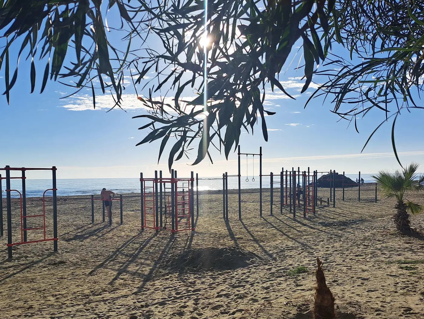 man doing calisthenics on the rings at kastella beach in larnaca, cyprus, at sunrise